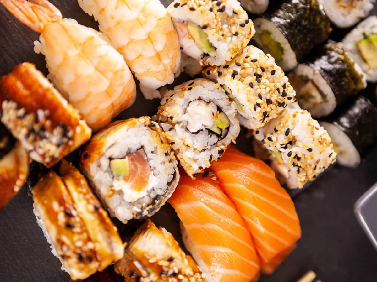 Zbliżenie na zestaw sushi: nigiri z krewetką i łososiem, uramaki w sezamie
