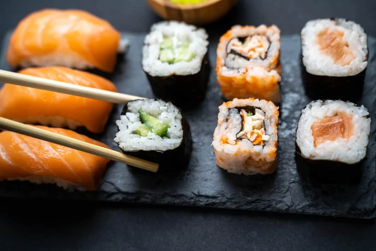 Nigiri z łososiem i maki na łupku, pałeczki podnoszą rolkę