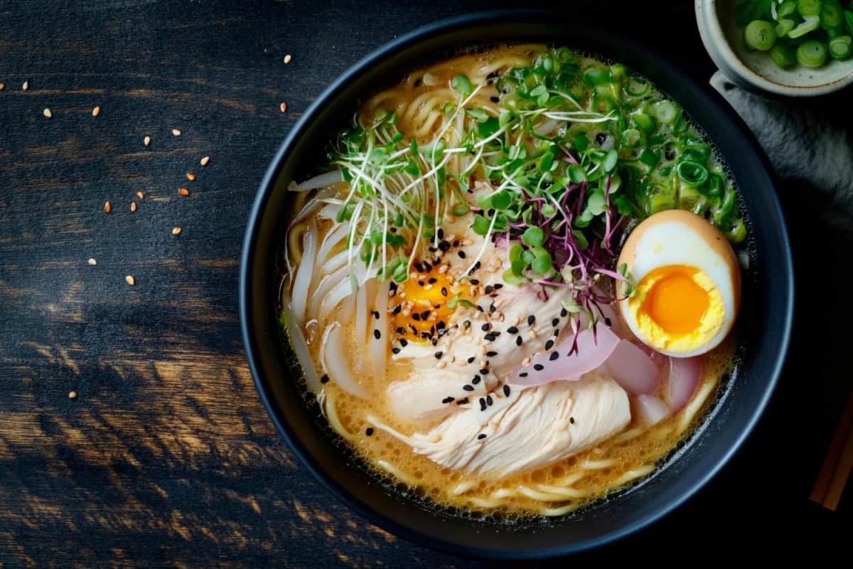 Ramen z kurczakiem, kiełkami, sezamem i jajkiem w czarnej misce